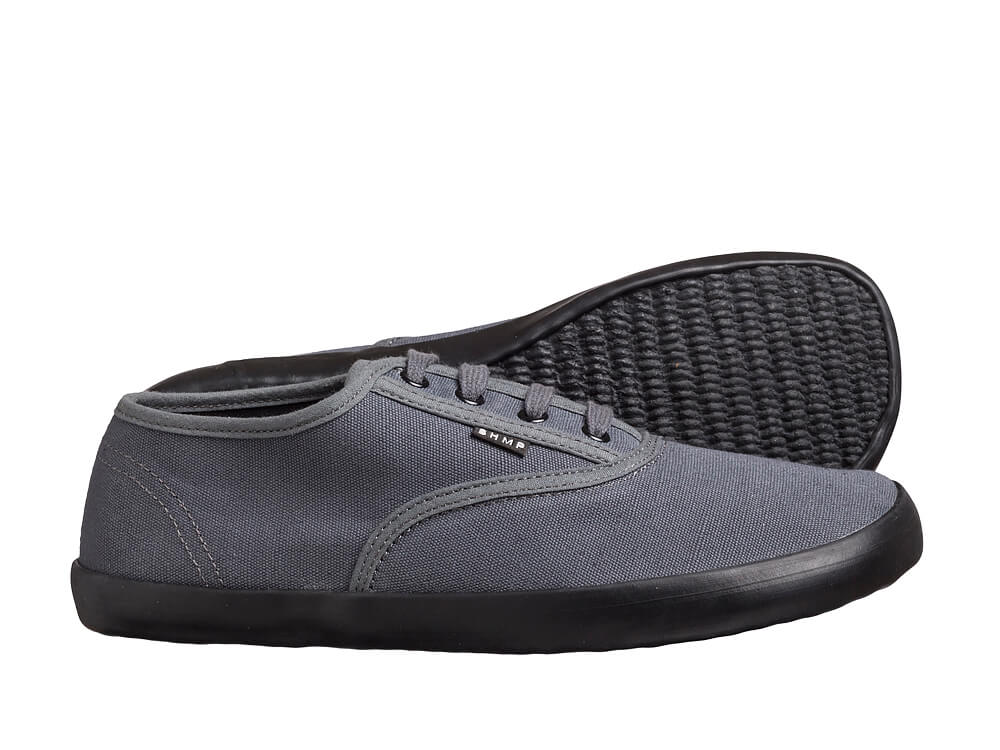 Grå sneaker med grå kantbånd, fire snørehuller og sort ydersål