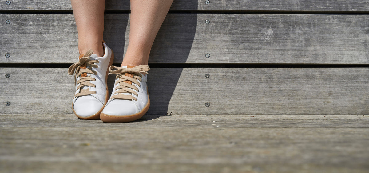 Par hvide sneakers set forfra på trætrin