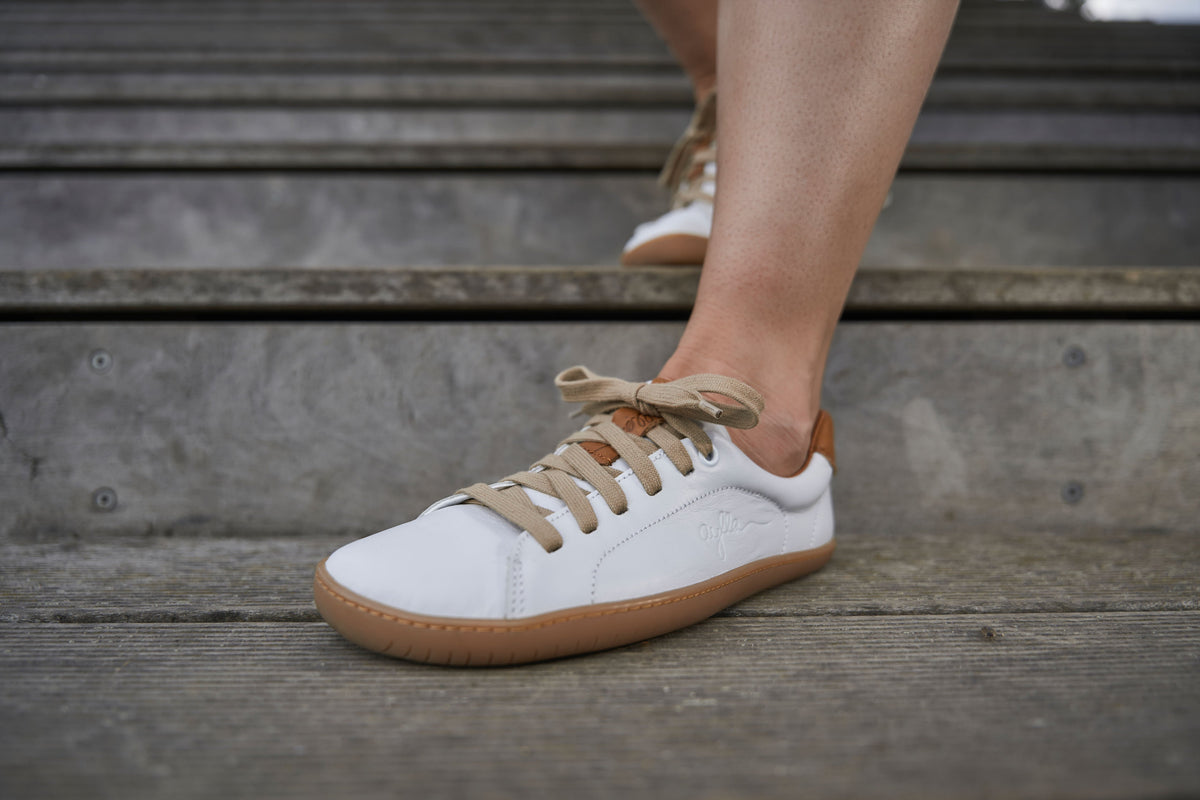 Hvid sneaker på fod med beige snørebånd i fokus