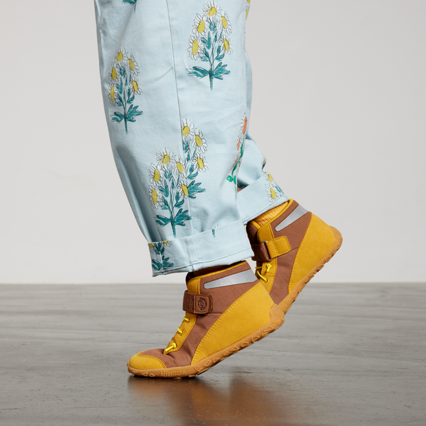Gulbrune sneakers på fødder i sidevendt studiebillede
