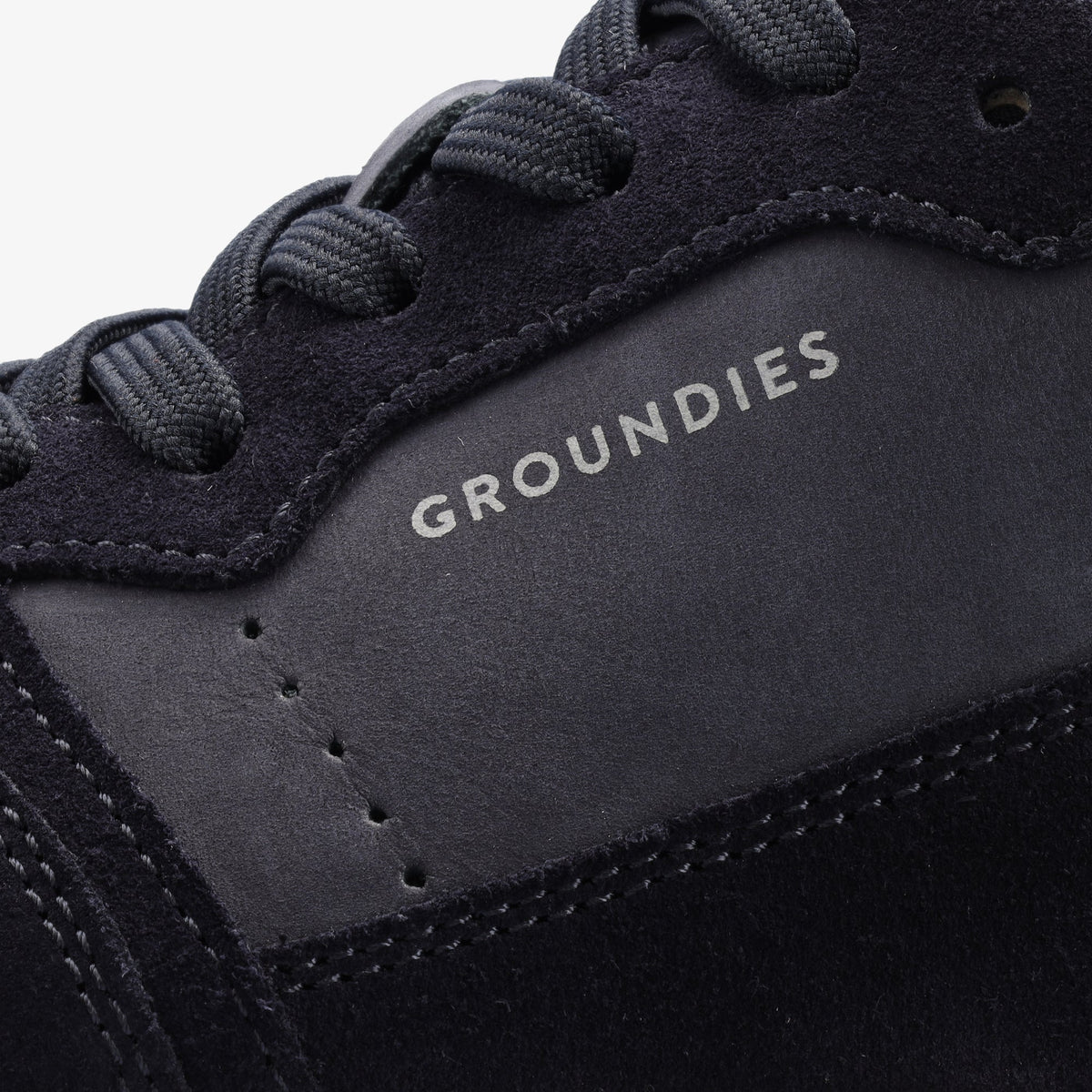 Nærbillede af Groundies-logo, perforering og navy snørebånd