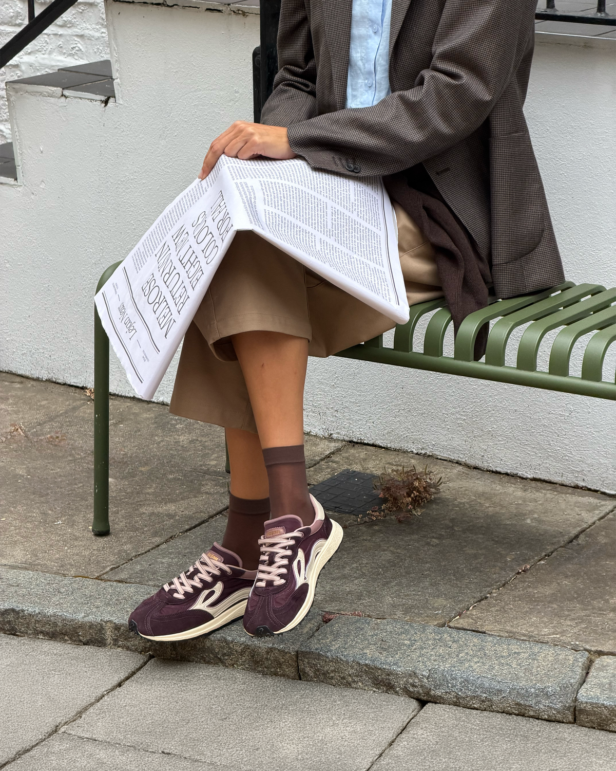 Kvinde på bænk med bordeaux sneakers på fødderne og brune strømper