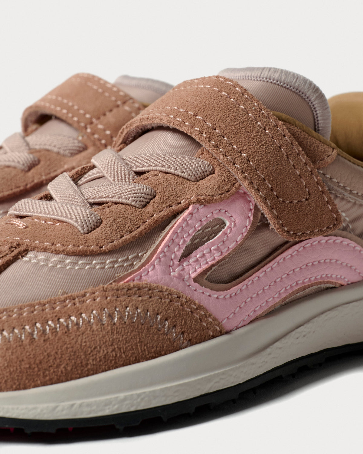 Nærbillede af velcrorem, snørebånd og lyserød bølgedetalje på rosa sneaker