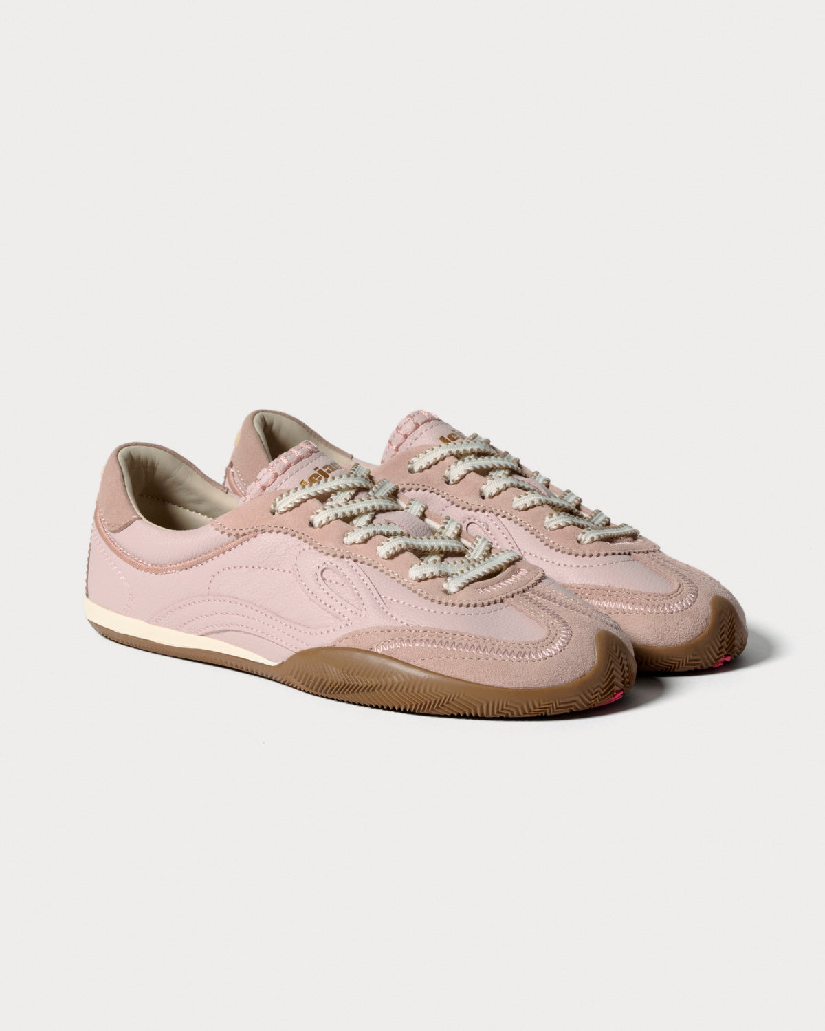 Par lyserøde sneakers med cremefarvede snørebånd set skråt forfra