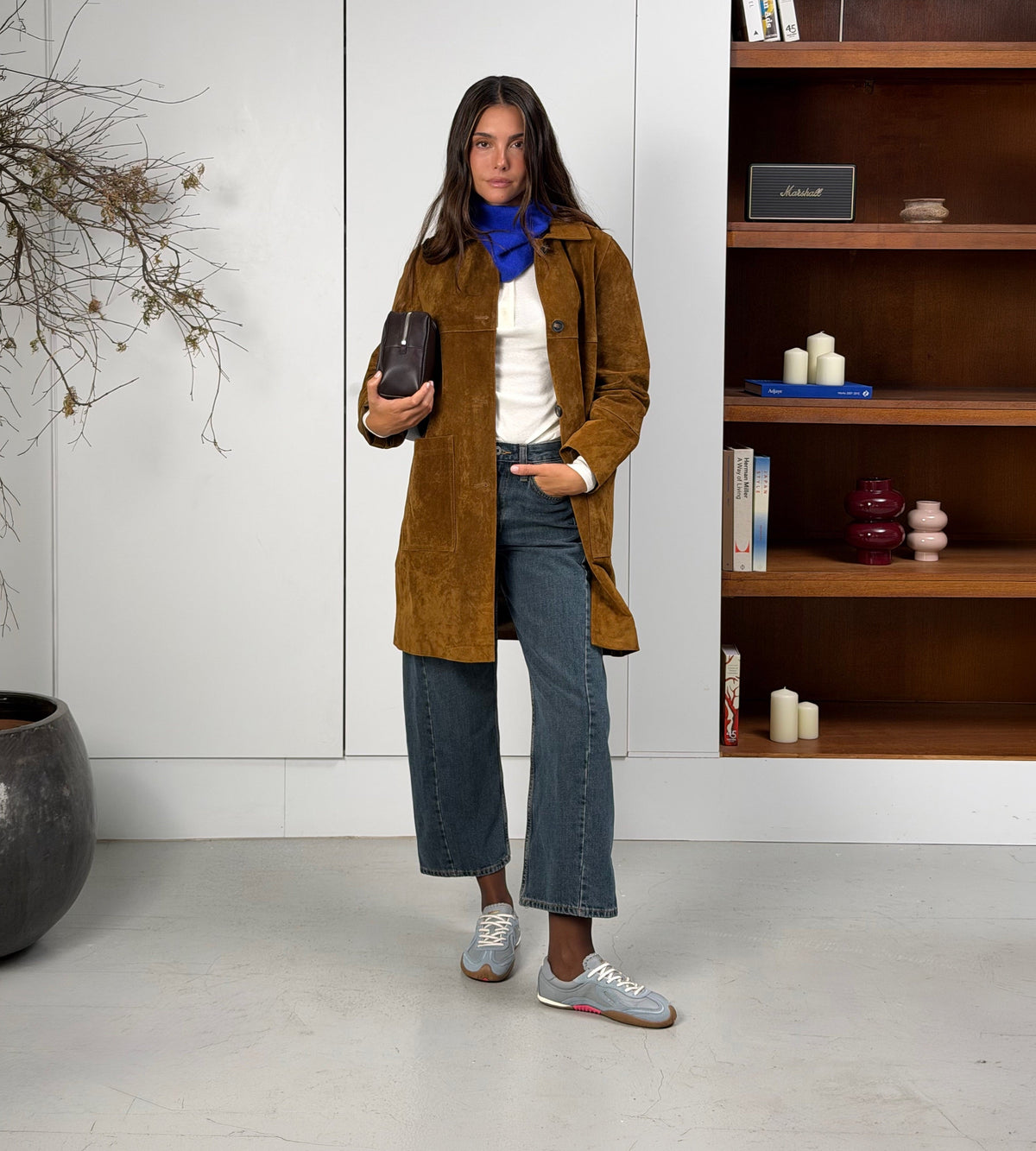 Lyseblå barfodssneakers på fod med jeans og brun jakke indendørs