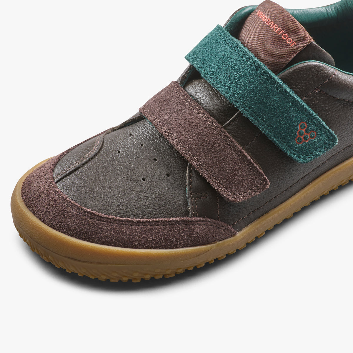 Nærbillede af to velcroremme i ruskind over forfoden på brun børnesneaker