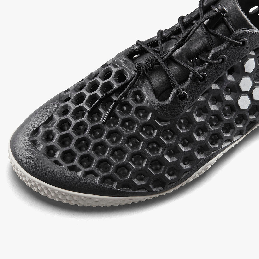 Vivobarefoot Ultra IV Womens sko i Obsidian variant med bikubemønster og traditionelt snøresystem. Minimalistisk design i sort med tekstureret sål for greb.
