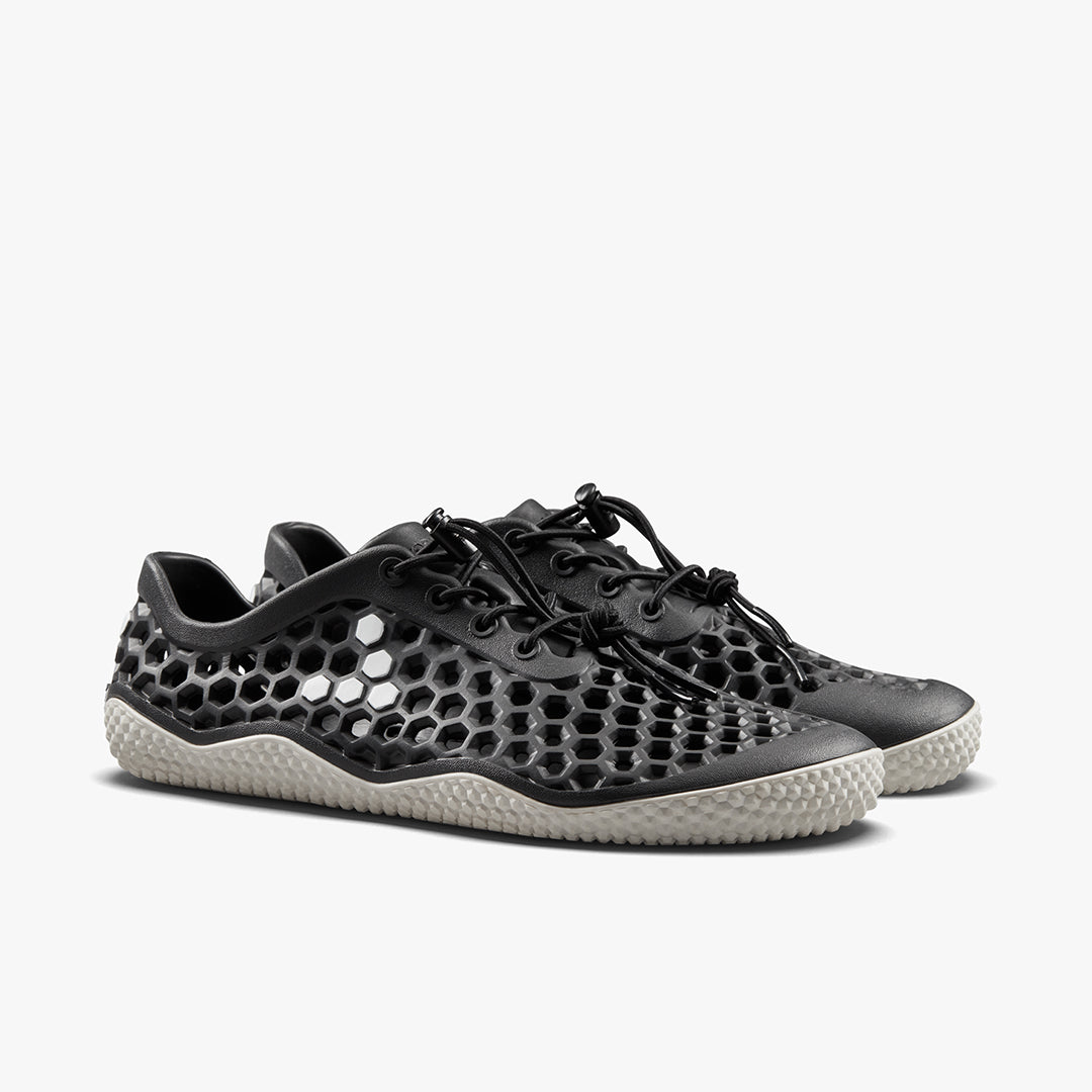 Vivobarefoot Ultra IV Womens sko i Obsidian. Sorte barfodssko med honningkage-mesh, minimalistisk snøresystem, og beige, tekstureret sål, ideel til udendørsaktiviteter.