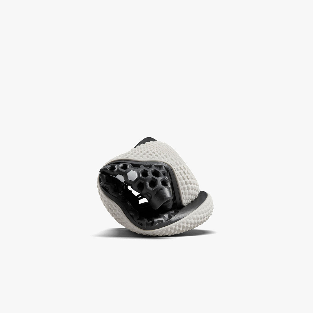 Vivobarefoot Ultra IV Womens sneaker i Obsidian variant rullet sammen for at vise fleksibilitet. Minimalistisk design med sort-honningfarvet sål og struktureret hvid overdel.