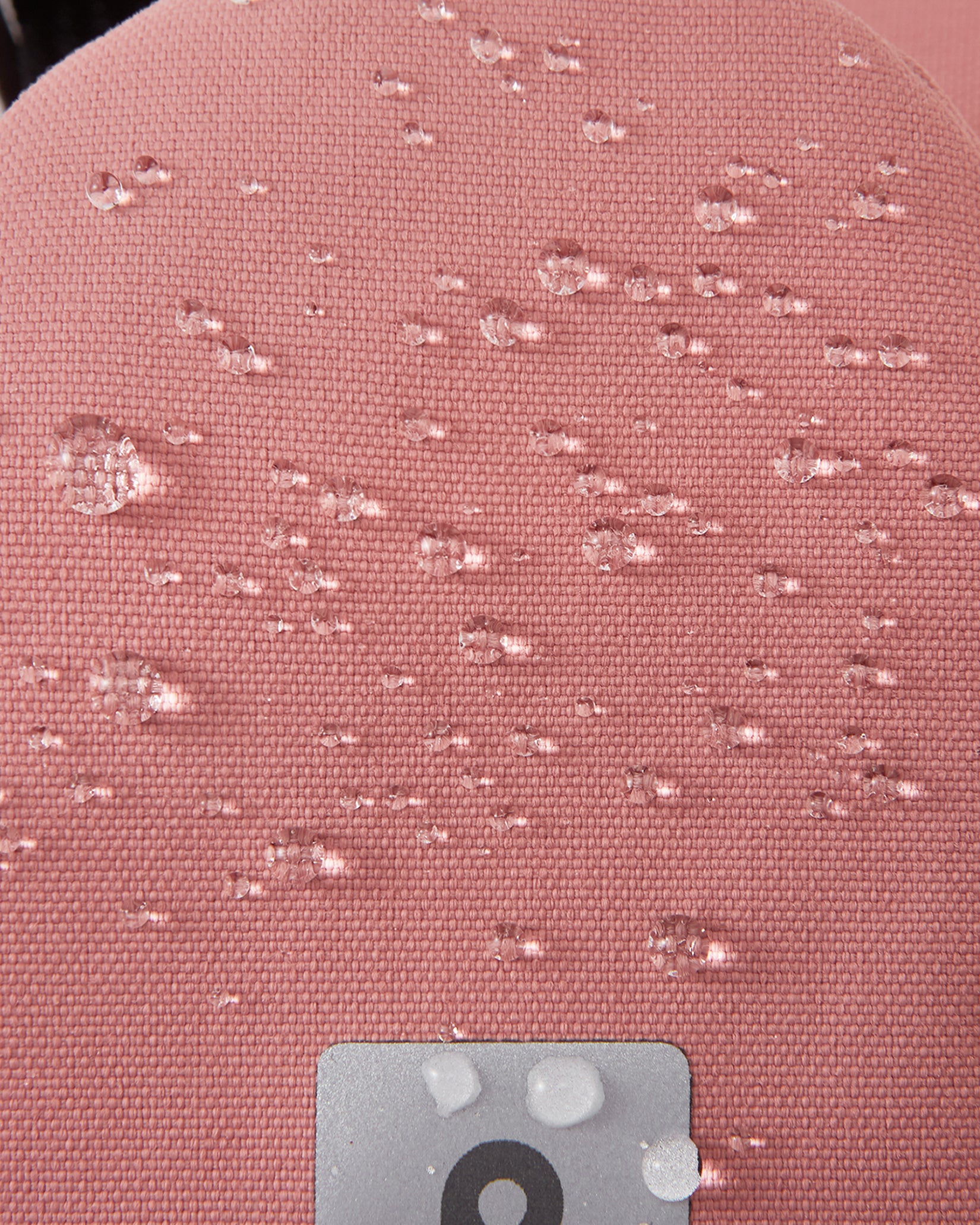 Reima Askare vanter til børn i Rose Blush, nærbillede af det vandtætte materiale med vanddråber
