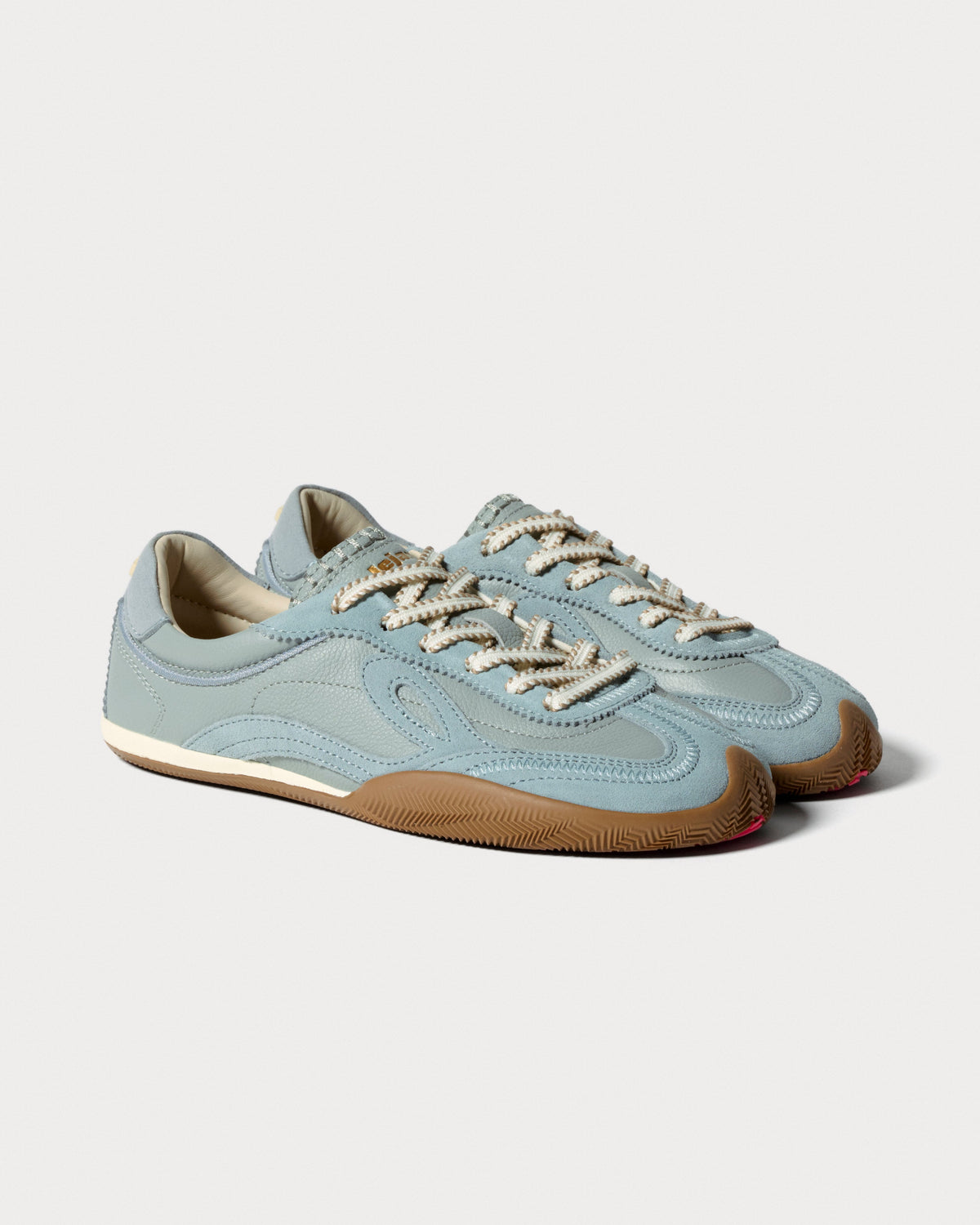 Par lyseblå sneakers med cremefarvede snørebånd set skråt forfra