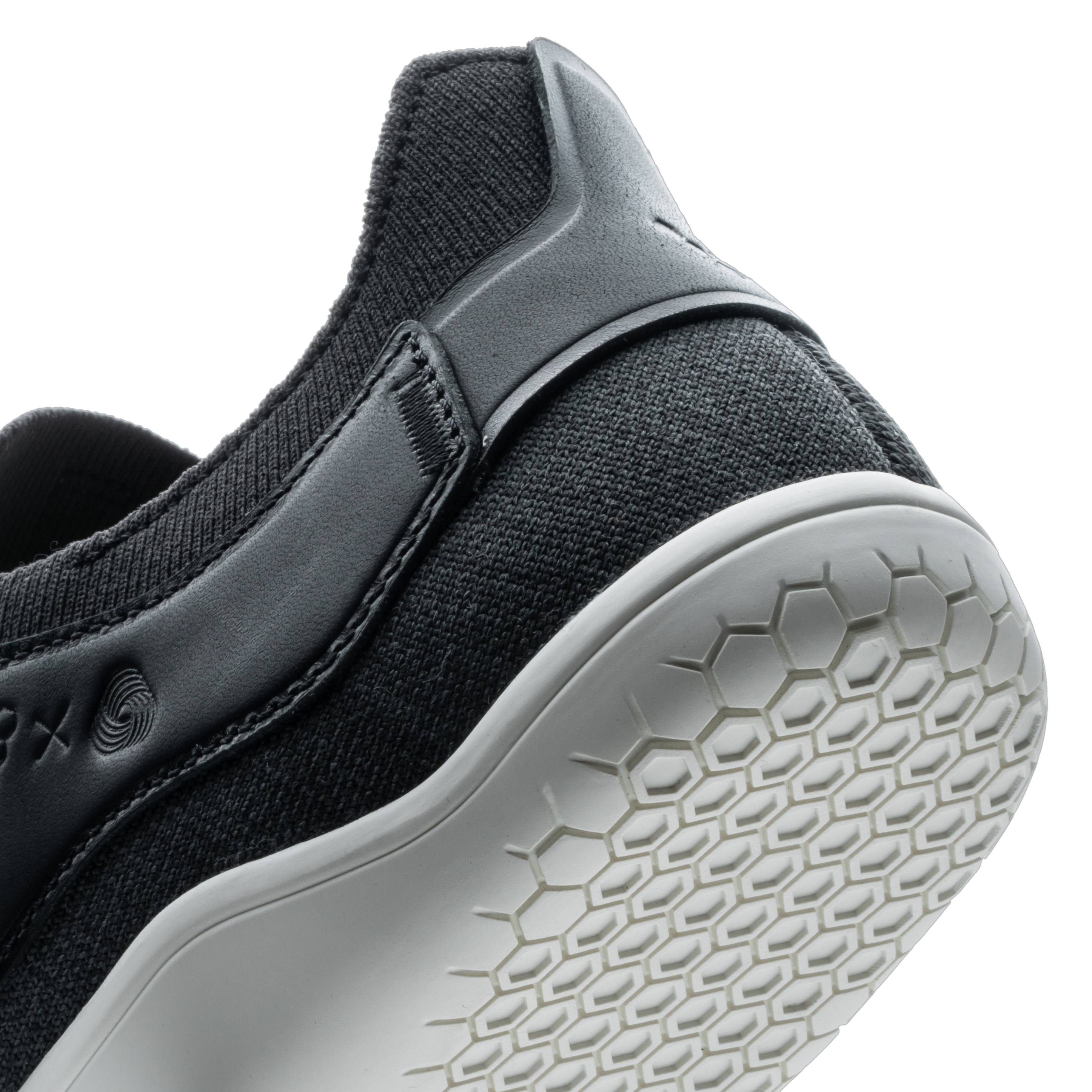 Vivobarefoot Asana III i varianten Obsidian, nærbillede af hælen og del af siden med fokus på det minimalistiske design og den tynde, fleksible ydersål af gummi, designet til at fremme naturlige gangmønstre.