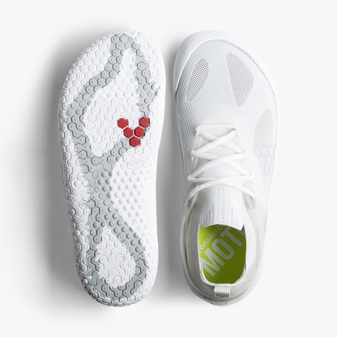 Vivobarefoot Motus Strength Womens i Bright White / Grey. Topvisning af den åndbare overdel og sidelæns visning af sålen med specielt greb. Barfodssko tenket til udendørs træning.