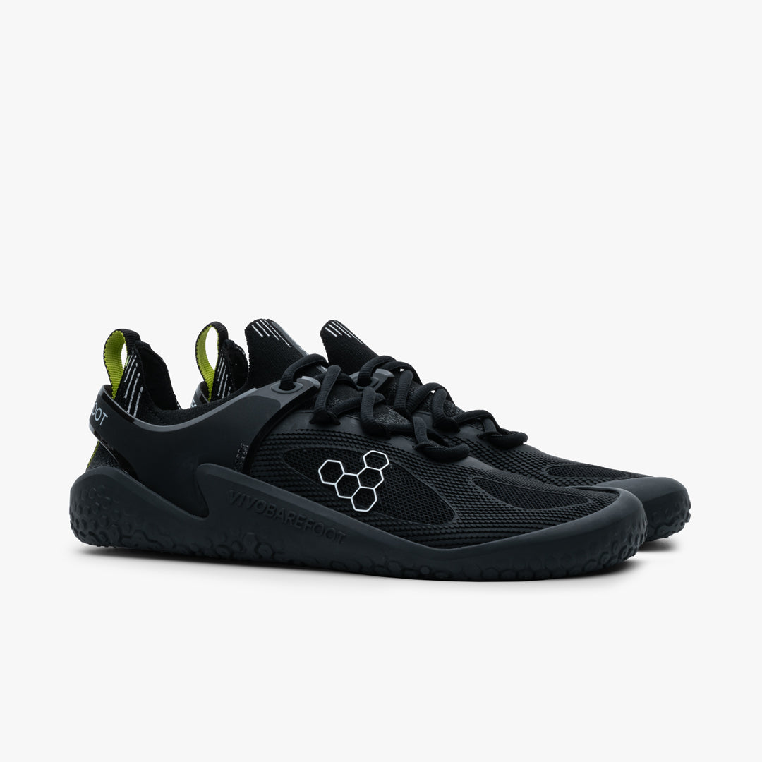 Vivobarefoot Motus Strength Womens i varianten Obsidian / Grey, designet til atletisk træning med en stram sort mesh-overdel og limegrønne trækfaner. Skoene har en tynd sål for at fremme naturlig fodbevægelse.